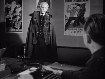 Movie still from “The Silence of the Sea” (1949), directed by Jean-Pierre Melville – A man standing in front of a mirror wearing a cape; Medium shot, Over the shoulder angle