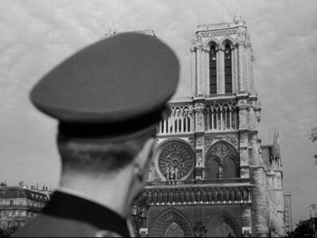 Movie still from “The Silence of the Sea” (1949), directed by Jean-Pierre Melville – A man in a military uniform standing in front of a building; Extreme Wide shot, Low angle
