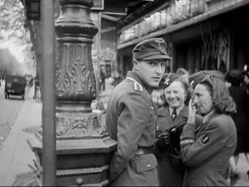 Movie still from “The Silence of the Sea” (1949), directed by Jean-Pierre Melville – A man and two women in uniform standing next to each other on the street; Medium shot, Over the shoulder angle