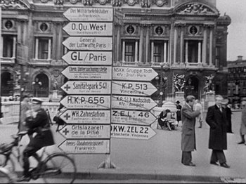 Movie still from “The Silence of the Sea” (1949), directed by Jean-Pierre Melville – An old photo of a bunch of street signs on a pole; Wide shot, High angle