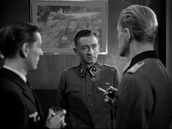 Movie still from “The Silence of the Sea” (1949), directed by Jean-Pierre Melville – A group of men standing next to each other in front of a painting; Medium shot, Over the shoulder angle