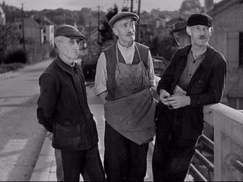Movie still from “The Silence of the Sea” (1949), directed by Jean-Pierre Melville – A group of men standing next to each other on a sidewalk; Medium shot, High angle