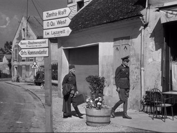 Movie still from “The Silence of the Sea” (1949), directed by Jean-Pierre Melville – A couple of men walking down a street; Wide shot, Over the shoulder angle