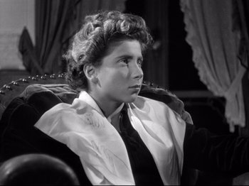 Movie still from “The Silence of the Sea” (1949), directed by Jean-Pierre Melville – A woman sitting in a chair wearing a neck tie; Close Up shot, High angle