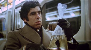 Movie still from “The Silent Partner” (1978), directed by Daryl Duke – A man holding a plastic bag while sitting on a train; Close Up shot, Low angle
