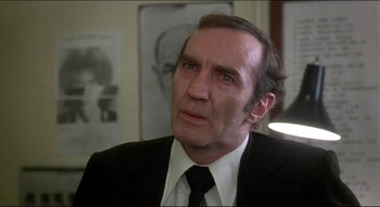 Movie still from “The Silent Partner” (1978), directed by Daryl Duke – An older man in a suit and tie looking to his left; Close Up shot, Over the shoulder angle