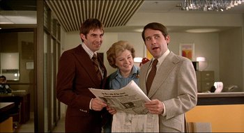 Movie still from “The Silent Partner” (1978), directed by Daryl Duke – A group of people standing next to each other holding a newspaper; Medium shot, Low angle
