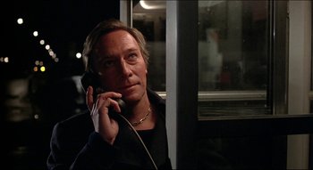 Movie still from “The Silent Partner” (1978), directed by Daryl Duke – A man is talking on a phone while sitting in a bus; Close Up shot, Low angle