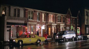 Movie still from “The Silent Partner” (1978), directed by Daryl Duke – A group of people standing next to cars on the side of the street; Extreme Wide shot, Low angle