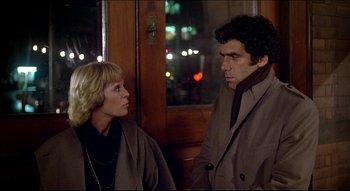 Movie still from “The Silent Partner” (1978), directed by Daryl Duke – A man and a woman standing next to each other in front of a window; Medium shot, Over the shoulder angle