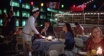 Movie still from “The Silent Partner” (1978), directed by Daryl Duke – Three people sitting at a table in front of a waiter; Wide shot, Over the shoulder angle