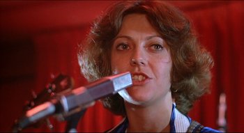 Movie still from “The Silent Partner” (1978), directed by Daryl Duke – A woman holding a remote control in her mouth; Close Up shot, Low angle