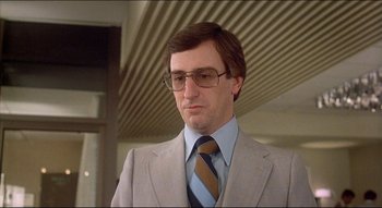 Movie still from “The Silent Partner” (1978), directed by Daryl Duke – A person wearing a suit and tie; Close Up shot, Low angle