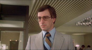 Movie still from “The Silent Partner” (1978), directed by Daryl Duke – A person wearing a suit and tie; Close Up shot, Low angle