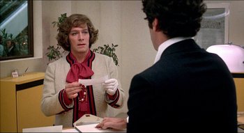 Movie still from “The Silent Partner” (1978), directed by Daryl Duke – A man holding a piece of paper in front of a mirror; Medium shot, Over the shoulder angle