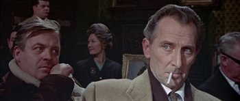 Movie still from “The Skull” (1965), directed by Freddie Francis – An older man smoking a cigarette in front of two other people; Close Up shot, Low angle