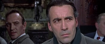 Movie still from “The Skull” (1965), directed by Freddie Francis – A person wearing a suit and tie; Close Up shot, Over the shoulder angle