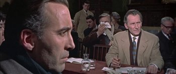 Movie still from “The Skull” (1965), directed by Freddie Francis – A group of people sitting at a table; Medium shot, Over the shoulder angle