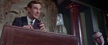 Movie still from “The Skull” (1965), directed by Freddie Francis – A man in a suit and tie holding a pipe in his mouth; Close Up shot, Low angle