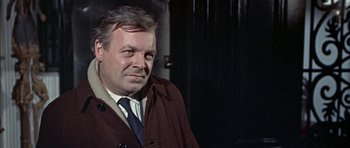 Movie still from “The Skull” (1965), directed by Freddie Francis – An older man wearing a jacket and tie; Close Up shot, Over the shoulder angle