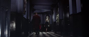 Movie still from “The Skull” (1965), directed by Freddie Francis – A man and a woman walking down a hall way; Wide shot, High angle