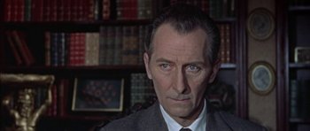 Movie still from “The Skull” (1965), directed by Freddie Francis – A person wearing a suit and tie; Close Up shot, Over the shoulder angle