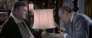 Movie still from “The Skull” (1965), directed by Freddie Francis – Two people looking at a lamp with a magnifying glass; Close Up shot, Over the shoulder angle