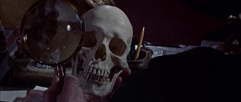 Movie still from “The Skull” (1965), directed by Freddie Francis – A person holding up a human skull with a magnifying glass; Extreme Close Up shot, Low angle