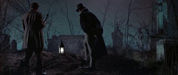 Movie still from “The Skull” (1965), directed by Freddie Francis – A man in a long coat and a hat walking in the dark; Wide shot, Low angle