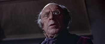 Movie still from “The Skull” (1965), directed by Freddie Francis – An old man with glasses is looking at the camera; Close Up shot, Low angle