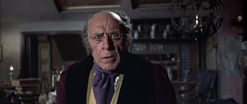 Movie still from “The Skull” (1965), directed by Freddie Francis – An old man wearing glasses and a purple bow tie; Close Up shot, Low angle