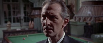 Movie still from “The Skull” (1965), directed by Freddie Francis – An older man in a black suit and white tie; Close Up shot, Over the shoulder angle