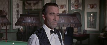 Movie still from “The Skull” (1965), directed by Freddie Francis – A person wearing a suit and bow tie; Close Up shot, Over the shoulder angle