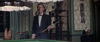 Movie still from “The Skull” (1965), directed by Freddie Francis – A man in a suit and tie holding a pool cue; Medium shot, High angle