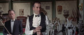 Movie still from “The Skull” (1965), directed by Freddie Francis – A man wearing a black vest and a bow tie; Medium shot, Low angle