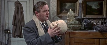 Movie still from “The Skull” (1965), directed by Freddie Francis – A man holding a human skull in his hands; Close Up shot, High angle