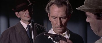 Movie still from “The Skull” (1965), directed by Freddie Francis – A person holding a gun; Close Up shot, Over the shoulder angle