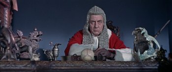 Movie still from “The Skull” (1965), directed by Freddie Francis – A man in a court robe and wig sitting at a table with a candle; Medium shot, Low angle