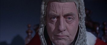 Movie still from “The Skull” (1965), directed by Freddie Francis – An older man wearing a judge's wig and wig; Close Up shot, High angle