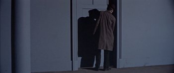 Movie still from “The Skull” (1965), directed by Freddie Francis – A man standing in front of an open door at night; Wide shot, High angle