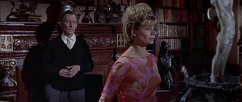 Movie still from “The Skull” (1965), directed by Freddie Francis – A man and a woman standing in front of a fireplace; Medium shot, Low angle