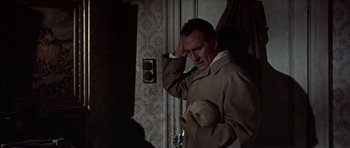 Movie still from “The Skull” (1965), directed by Freddie Francis – A man holding a teddy bear standing in front of a door; Medium shot, Low angle