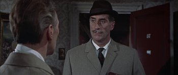 Movie still from “The Skull” (1965), directed by Freddie Francis – A person wearing a suit and a hat; Close Up shot, Over the shoulder angle