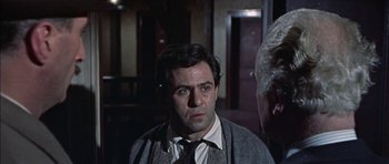 Movie still from “The Skull” (1965), directed by Freddie Francis – A person wearing a suit and tie; Close Up shot, Over the shoulder angle