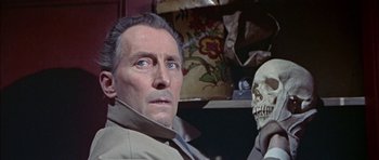 Movie still from “The Skull” (1965), directed by Freddie Francis – A person with a skull in a room; Close Up shot, Over the shoulder angle