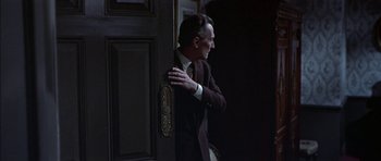 Movie still from “The Skull” (1965), directed by Freddie Francis – A man in a suit leaning against a door; Medium shot, Low angle