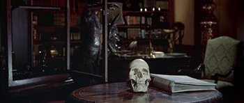 Movie still from “The Skull” (1965), directed by Freddie Francis – A skull on a table in a room; Medium shot, High angle