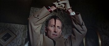 Movie still from “The Skull” (1965), directed by Freddie Francis – A man in a trench coat holding a whip; Close Up shot, Overhead angle