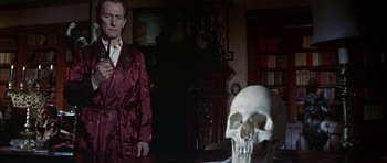 Movie still from “The Skull” (1965), directed by Freddie Francis – A man standing in front of a skull in a room; Medium shot, Over the shoulder angle