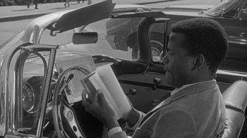 Movie still from “The Slender Thread” (1965), directed by Sydney Pollack – A black and white photo of a man driving a car; Close Up shot, High angle